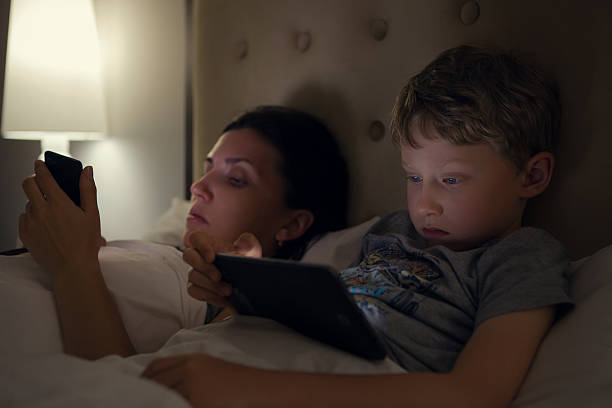 istock Mother with son looks in their electronic devices lying in bed 488910134