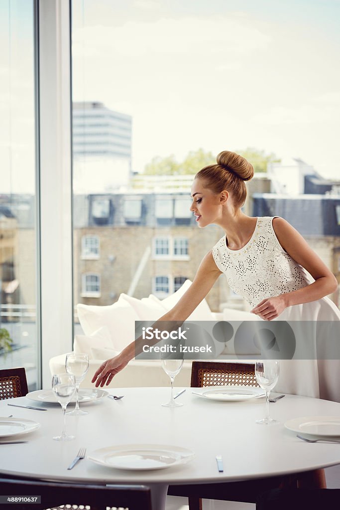 Arranging dining table Elegant woman arranging a dining table in her posh apartment. Arranging Stock Photo