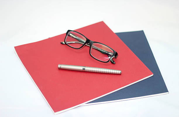 blaue und rote notizbuch und stift mit eyeglasses grau - three objects personal organizer book pen stock-fotos und bilder