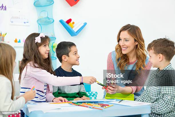 Female Teacher Drawing And Coloring With Children In The Kindergarden Stock Photo - Download Image Now