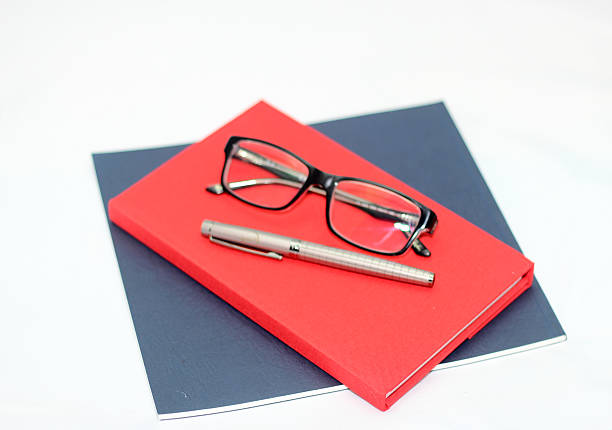 blaue und rote notizbuch und stift mit eyeglasses grau - three objects personal organizer book pen stock-fotos und bilder