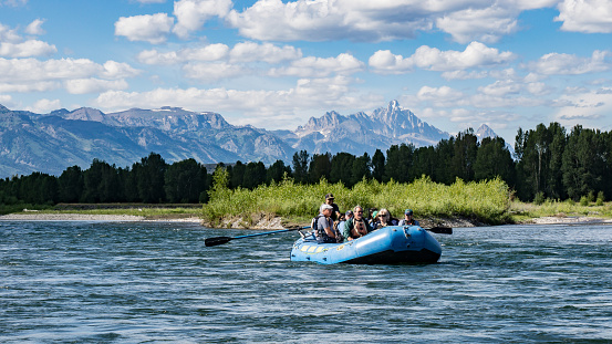 Jackson, Wyoming, USA- July 19, 2015: a group of tourists take a rafting excursion on the Snake River near Jackson, Wyoming. Along the way are numerous eagles and large mammals such as elk that can be spotted from the rafts. The Grand Teton Mountains can be seen in the distance.