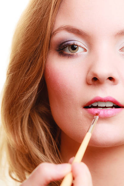 Part of face. Woman applying pink lipstick with brush Cosmetic beauty procedures and makeover concept. Closeup part of woman face pink lips. Make-up artist applying lipstick with accessories tools. make over series stock pictures, royalty-free photos & images