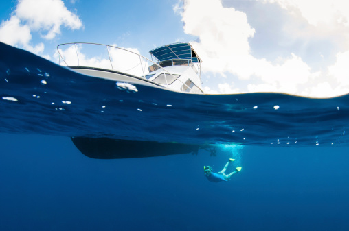 A woman diving under the boat in Bonaire