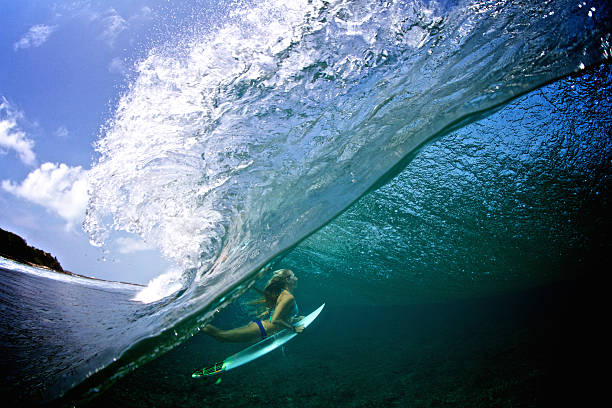 Half over half under girl duck diving a breaking wave
