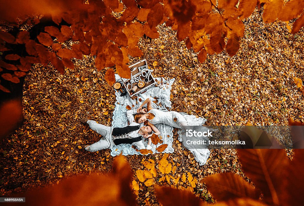 wedding couple lying under a tree Beautiful wedding couple lying under a tree Autumn Stock Photo