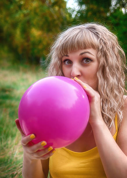istock beautiful woman is blowing up a balloon 488957138