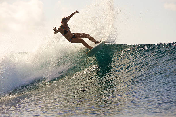 istock Sunrise surfer girl does turn to send spray 488960866
