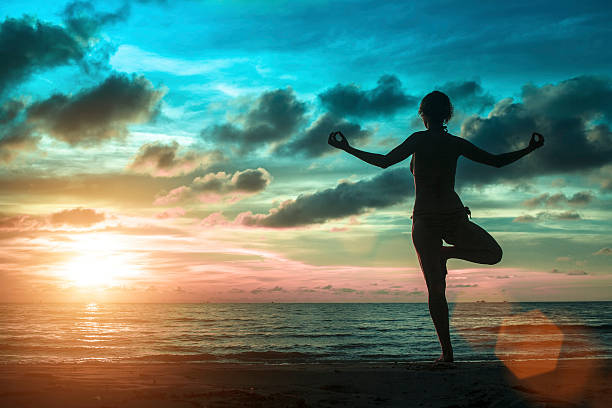 istock women standing at yoga pose on the beach 488961176