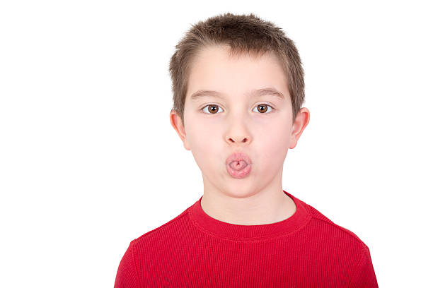 Young boy sticking out his tongue Playful young boy sticking out his tongue in a mischievous gesture or in an act of rudeness isolated on white derogatory stock pictures, royalty-free photos & images