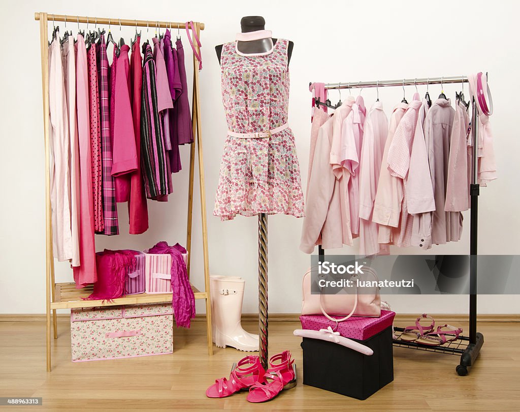 Wardrobe with all shades of pink clothes, shoes and accessories. Dressing closet with pink clothes arranged on hangers and an outfit on a mannequin. Arranging Stock Photo