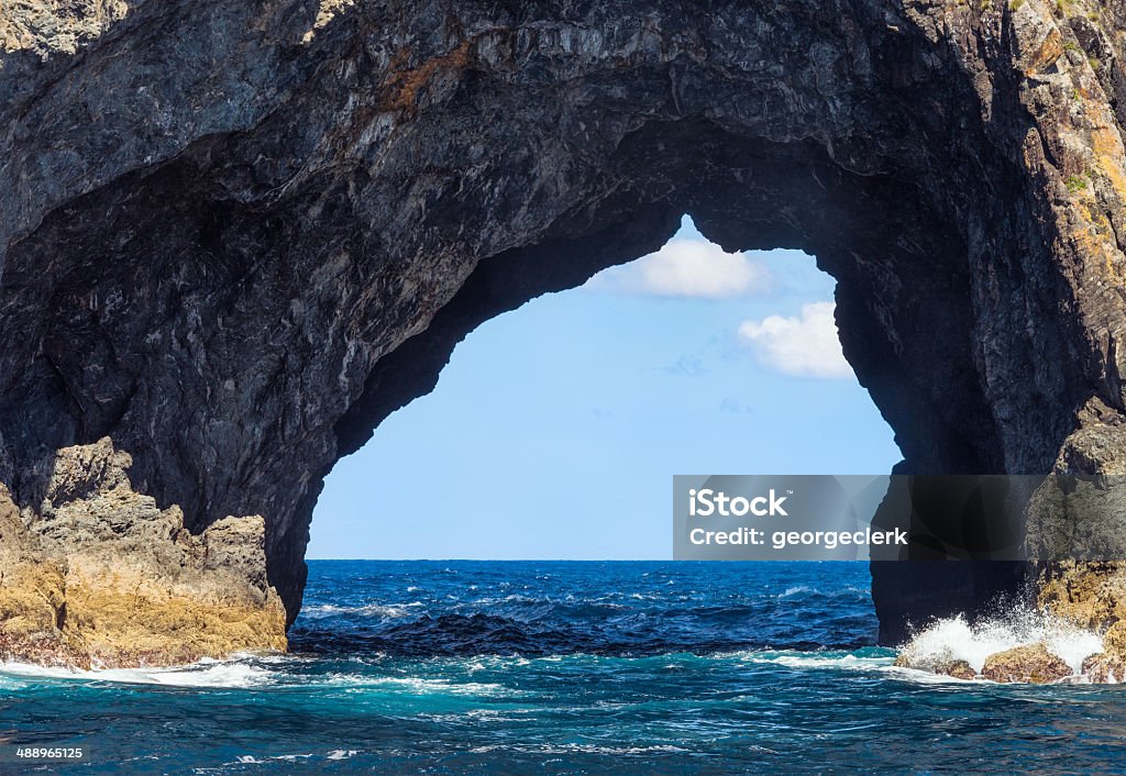 Hole in the Rock The famous 'Hole in the Rock', part of Piercy Island, a small island located on the outskirts of the Bay of Islands in New Zealand's Northland.  Cave Stock Photo