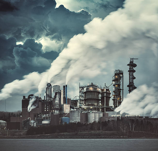 Distant passenger plane flies behind a cloud of Cardon Dioxide coming out of towers from the combustion of natural gas at a steel plant at IJmuiden on the north coast of the Netherlands