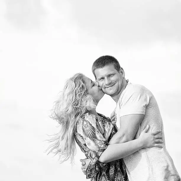 Photo of monotone shot of happy couple in love on the beach