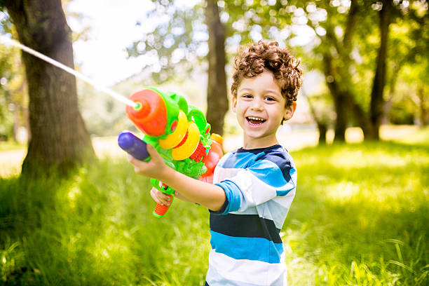 niño jugando con pistola de agua - pistola de agua fotografías e imágenes de stock