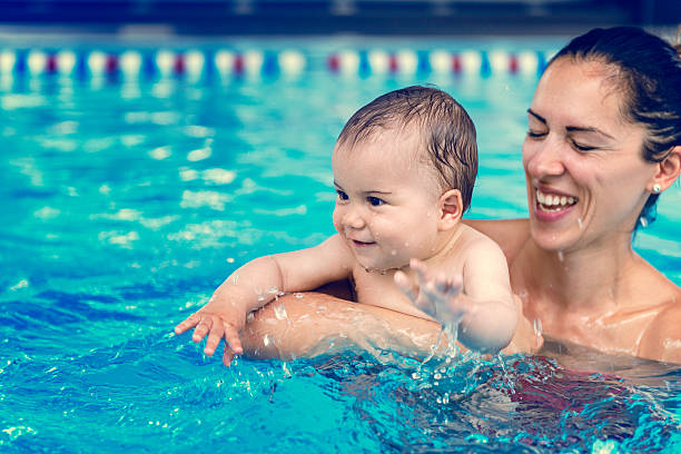 bebé niño con su madre en la piscina - bebe bañandose fotografías e imágenes de stock