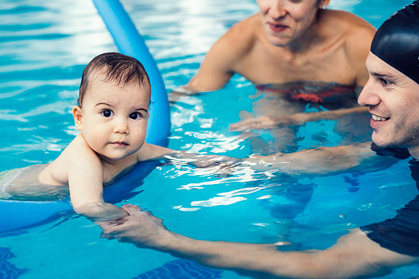 istock Instructor with baby boy and his mother on swimming class 488980518