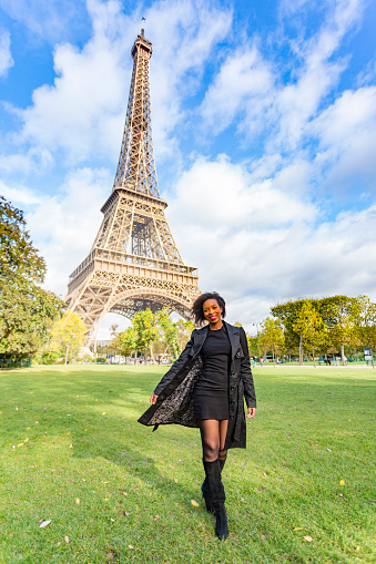 Happy and stylish young African woman walking in Paris with the Eiffel Tower