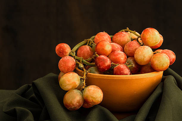 Bowl of grapes against dark background stock photo
