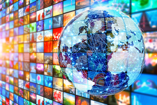 Media wall with a pattern of colorful images resembling a television broadcasting concept with planet Earth in front of it, connected by a global network, with glowing nodes and surrounding links. Hundreds of color video stills projected on television displays around the world, as a metaphor of video entertainment and global communications. 
