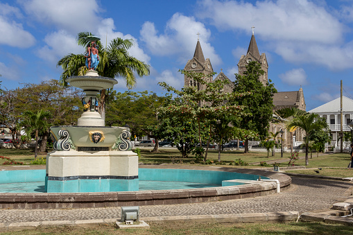 View on a fountain and a catholic church in the background at Independence Square at Basseterre, St. Kitts island, Caribbean. 