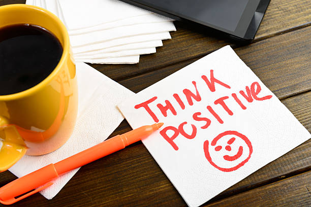 Think positive writing on white napkin Think positive writing on white napkin around coffee pen and phone on wooden table positive emotion stock pictures, royalty-free photos & images