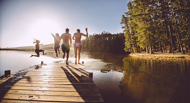 istock Four people jumping off a jetty into the water 488997683