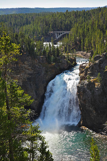 Beautiful falls and the bridge on rough northern river in forest