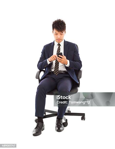 Handsome Businessman Touching Smart Phone On Chair Stock Photo - Download Image Now - Adult, Adults Only, Asia