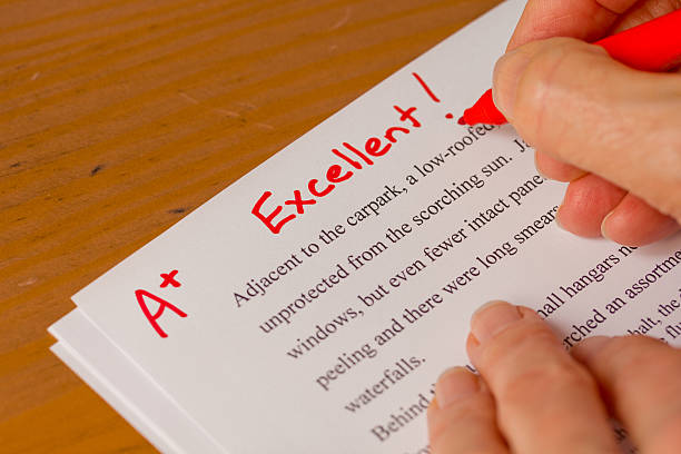 Hand and Red Pen Grading Papers with Excellent stock photo