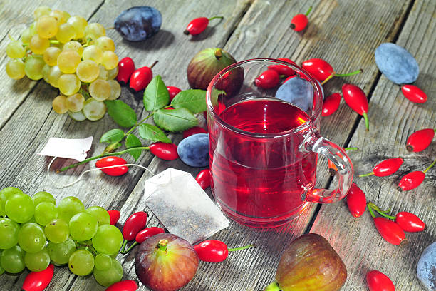 Dog rose tea and autumn fruits Photo of dog rose tea and autumn fruits on a wooden tabe wild rose hip stock pictures, royalty-free photos & images