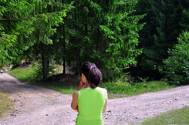 menina com uma opção junto à rua bifurcada - footpath field nature contemplation imagens e fotografias de stock