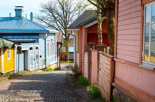 Porvoo, Finland - May 10, 2015: Street view in the old part of the city on a sunny spring day. Wooden empire-style homes painted in yellow, blue, red or pink surround the cobblestone-paved street. 