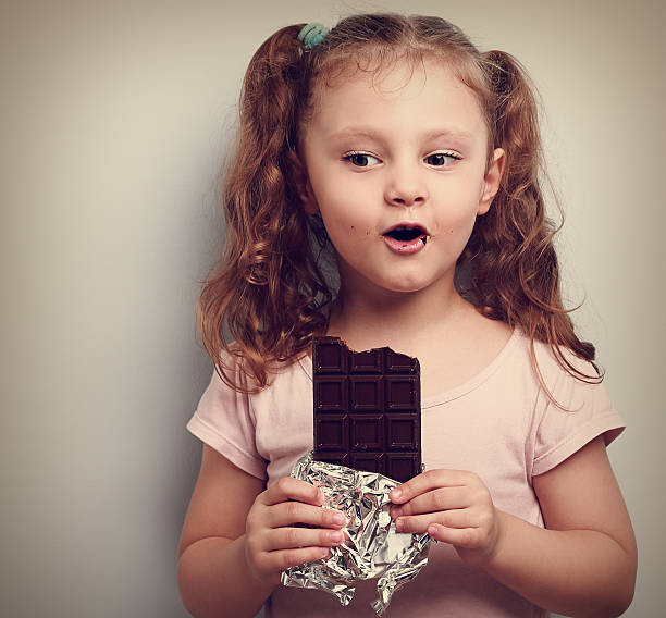 istock Fun kid girl eating dark chocolate 489010436