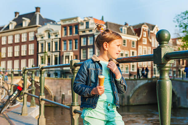 Outdoor portrait of a cute little girl looking on a beautiful canal in Amsterdam