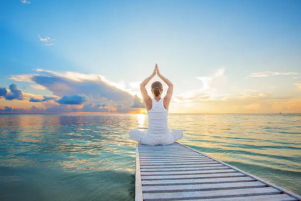 Photo of Caucasian woman practicing yoga at seashore