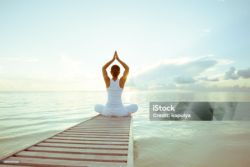 Caucasian woman practicing yoga at seashore Order Stock Photo