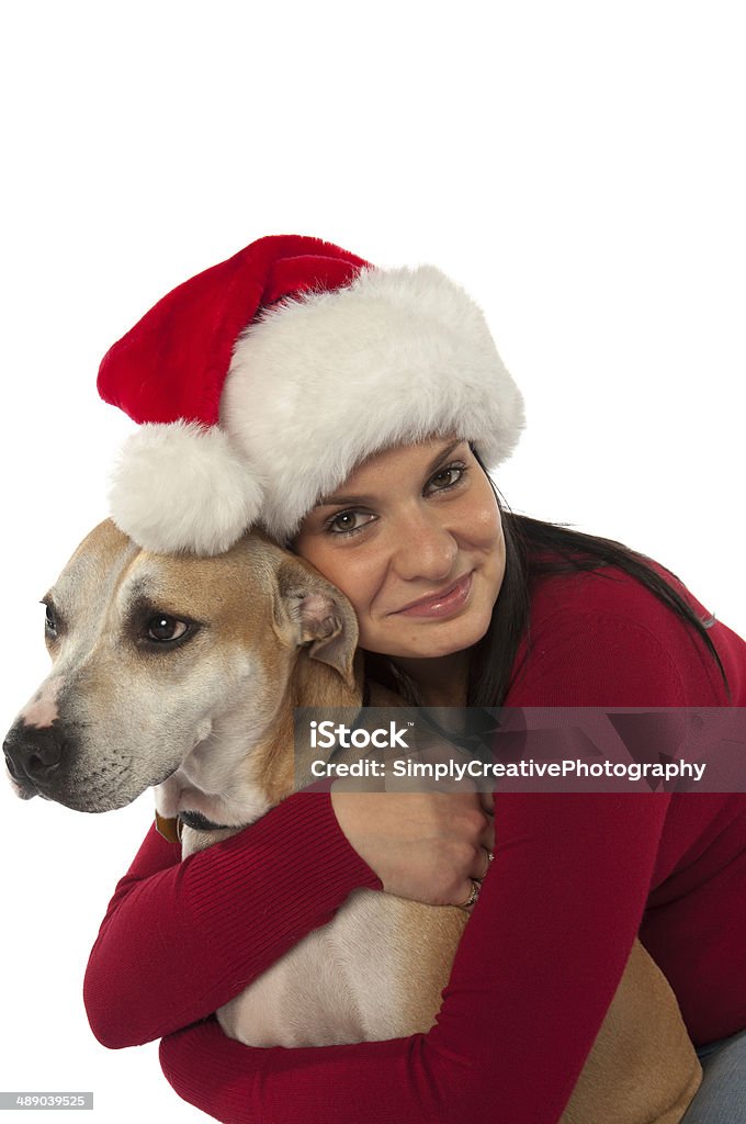 Woman In Santa Claus Hat Hugging Dog A young woman wearing a santa hat hugs her dog. (Toronto minLypse 2010) Adult Stock Photo