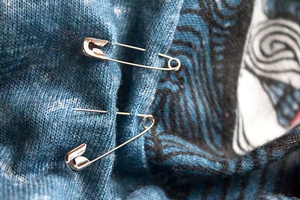 Safety pins on the blue fabric stock photo