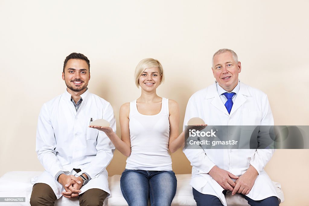 doctor with patient, woman show breast implant, plastic surgery clinic doctor with yong woman patient smile, show breast implant, sitting at plastic surgery hospital medical clinic Adult Stock Photo