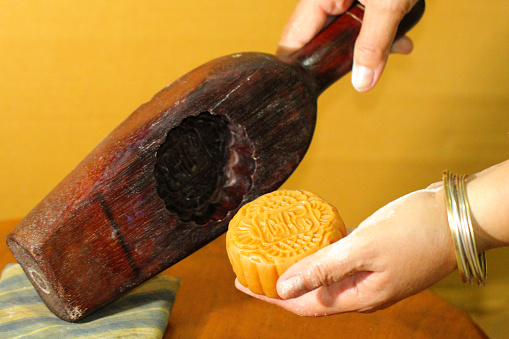 Process of removing moon cake from wooden mold with close up old women's hands at Bakery shop