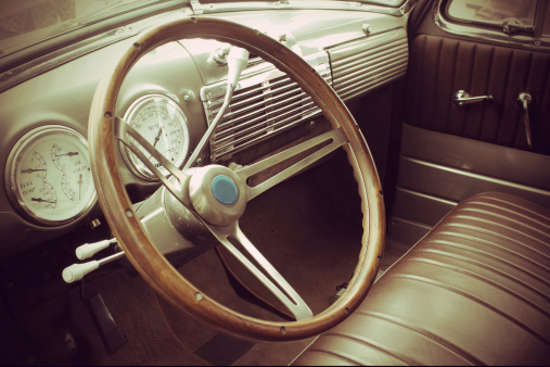 Beautiful wooden steering wheel and and old-fashioned small gauges and large beautiful exterior mirror of a historic cabriolet - right-hand drive