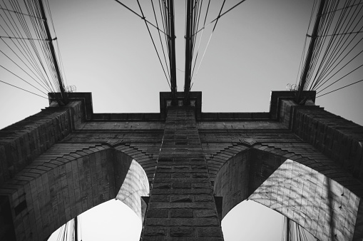 View from the bottom of one the two neo-Gothic pillars of Brooklyn Bridge with steel cables.