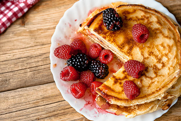 Delicious pancakes with berries on the wooden table