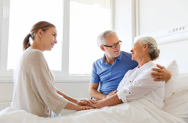 szczęśliwa rodzina odwiedzając senior kobieta w szpitalu - senior adult family hospital visit zdjęcia i obrazy z banku zdjęć