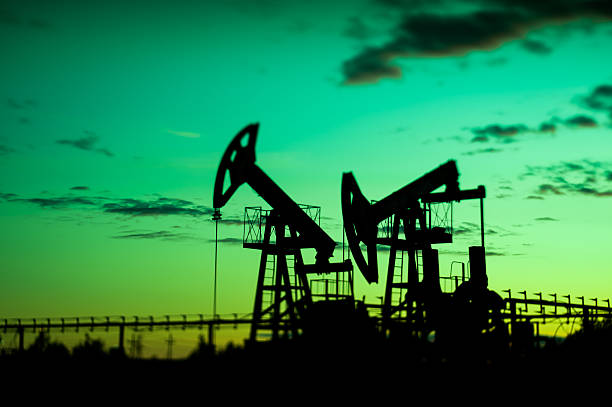 Oil pumps. Oil pump jacks at sunset sky background. Selective focus, shallow depth of field. wellhead stock pictures, royalty-free photos & images