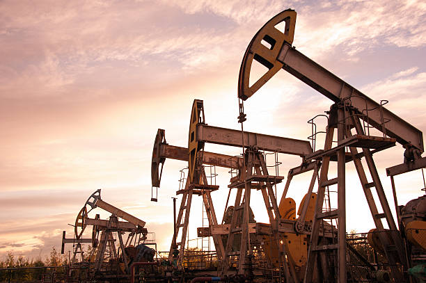 Oil pumps. Oil pump jacks at sunset sky background. Toned. crude oil stock pictures, royalty-free photos & images