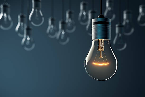 Glowing Hanging Light Bulb Hanging glowing light bulb on blue background fuel and power generation photos stock pictures, royalty-free photos & images
