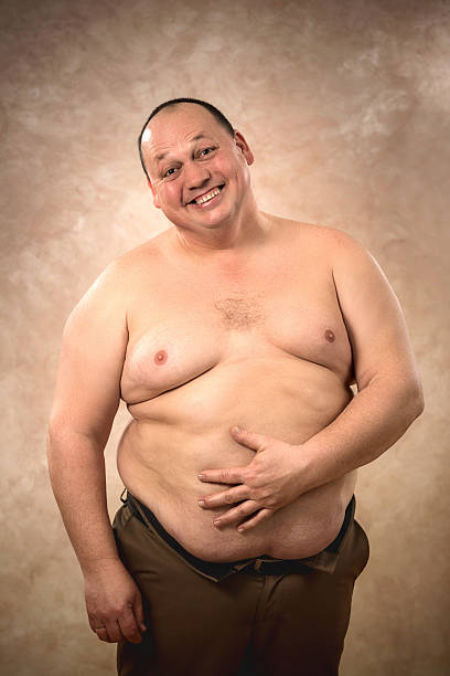 Portrait of cheerful shirtless fat man looking at camera. Happy shirtless overweight man standing and looking at camera. fat guy no shirt stock pictures, royalty-free photos & images