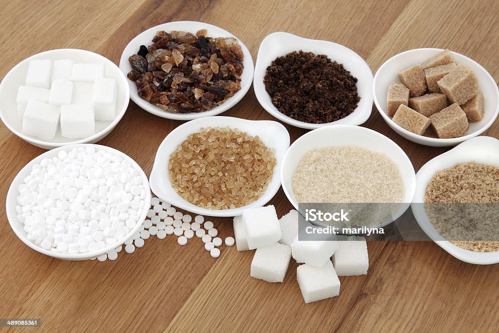 Sugar Types Sugar selection in white porcelain dishes over oak background. Addiction Stock Photo